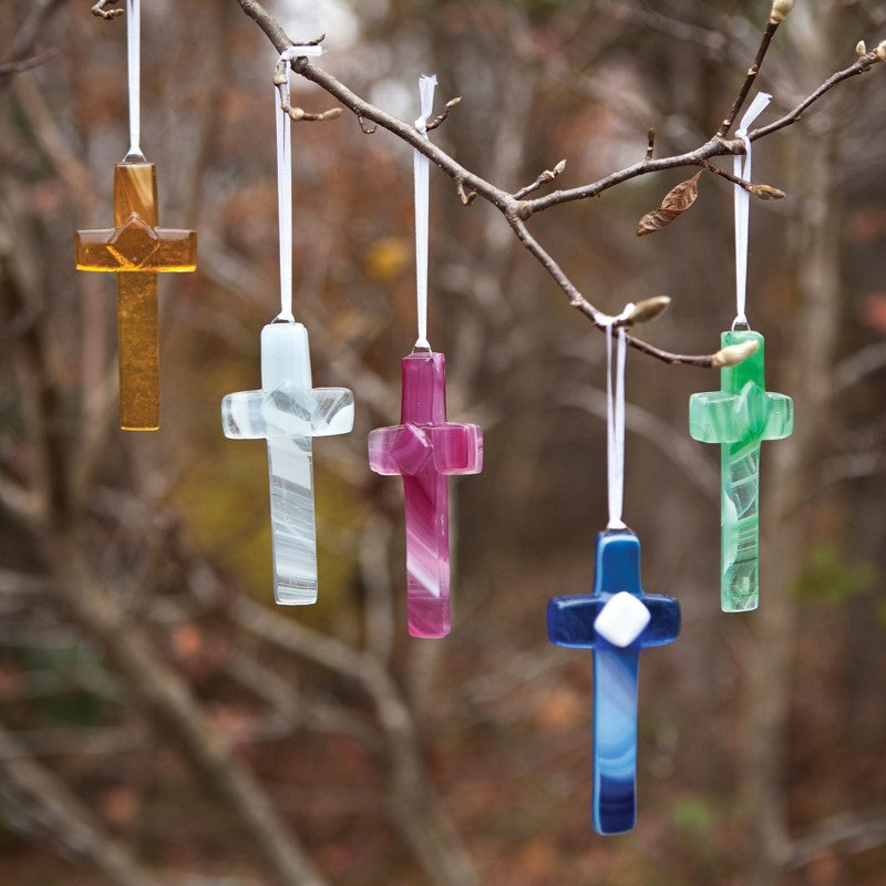 An assortment of glass crosses hanging in a tree.