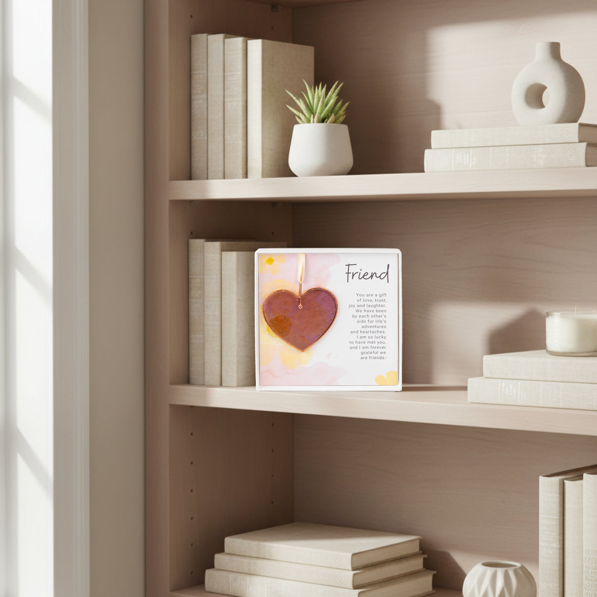 Pink rose mauve glass heart gift for friend on a bookshelf.