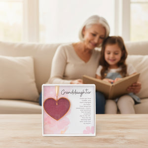 2 of 6:Granddaughter gift on a table with a grandma and her granddaughter in the background reading a book together.