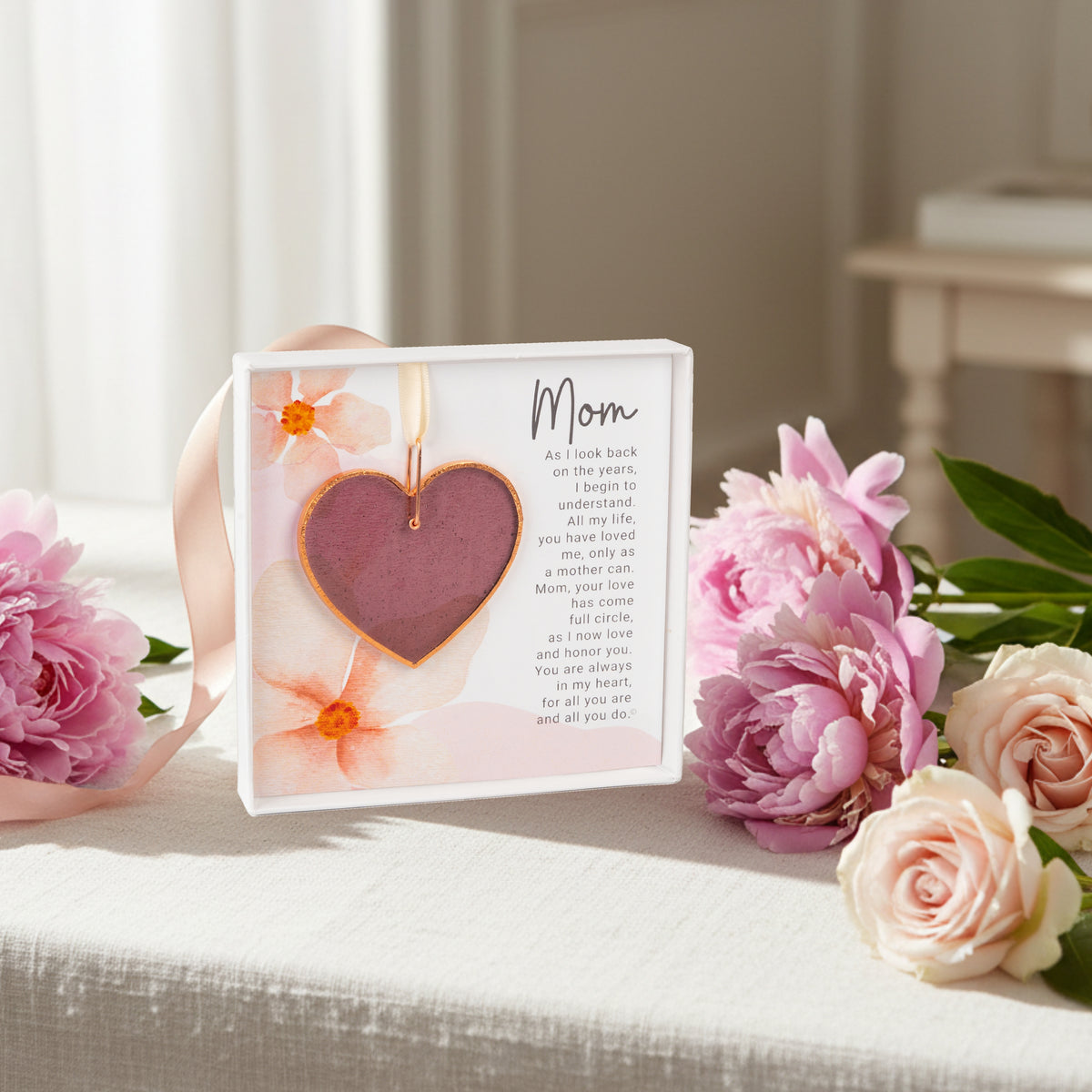Mom artwork with sentiment and pink stained glass heart on a table with flowers.