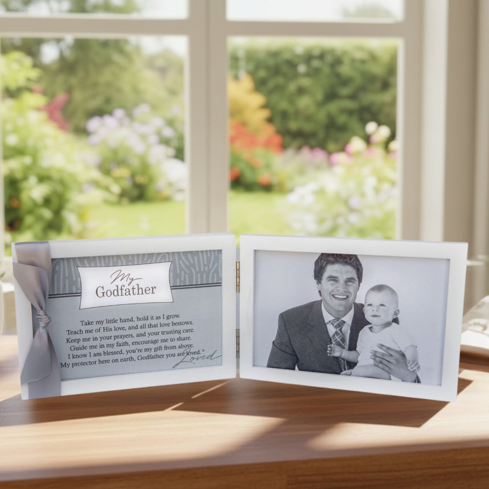 White 4x6 double wood frame with "My Godfather" sentiment and gray satin ribbon on the left and space for a photo on the right. Frame on a desk in front of a garden window.