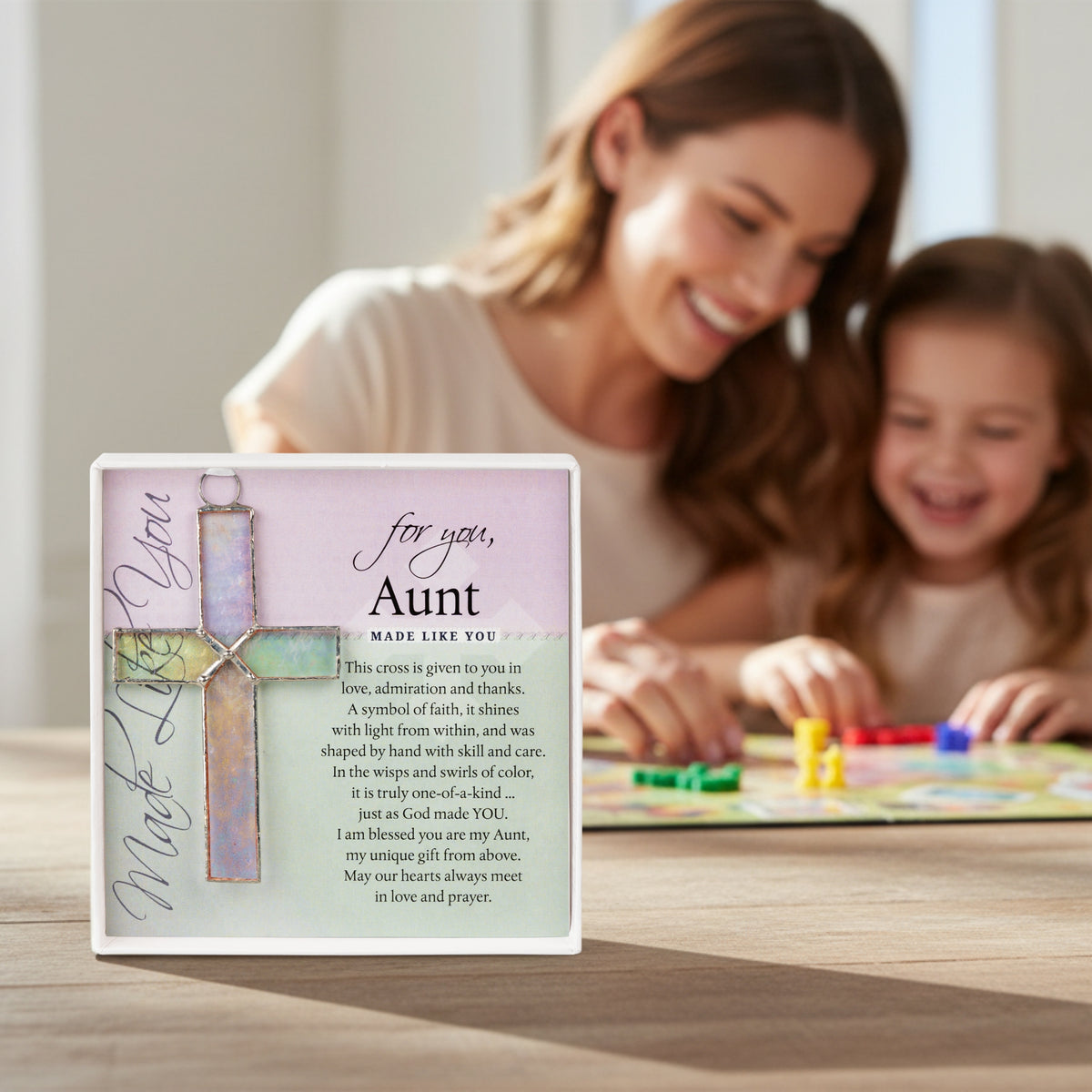 "For You Aunt" cross on a table with an aunt and her niece playing a game in the background.