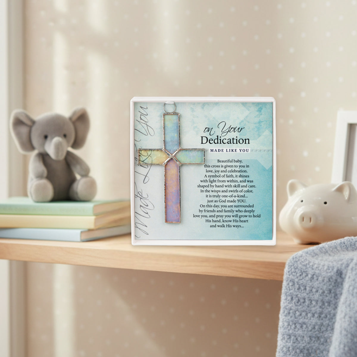 "On Your Dedication" glass cross gift on a shelf in a baby's room.