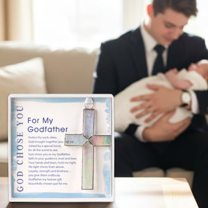5 of 5:Godfather gift on a table with a Godfather holding his godchild in the background.