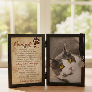 2 of 8:Pawprints Left by You cat frame on a table in front of a window.