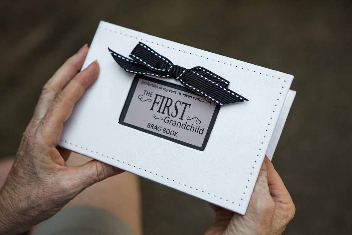 The First Grandchild Brag Book being held in hands.