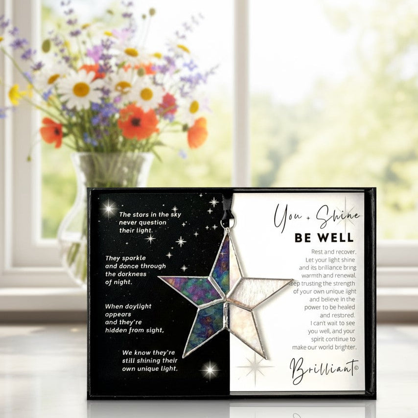 Handmade 4" clear iridescent stained glass star with silver edging, packaged with "You + Shines Be Well" sentiment in black gift box with clear lid.