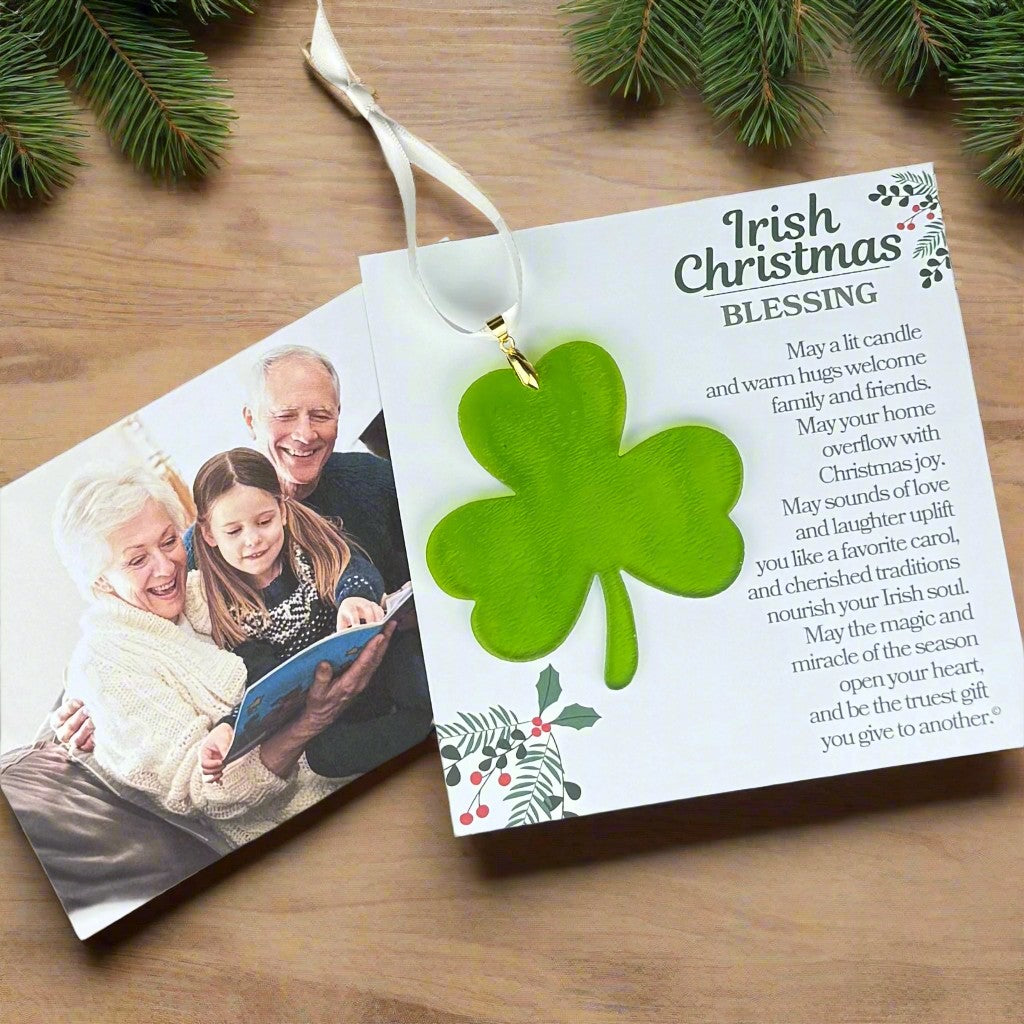 Irish Christmas blessing card with a green shamrock and photo of a family on a wooden surface.