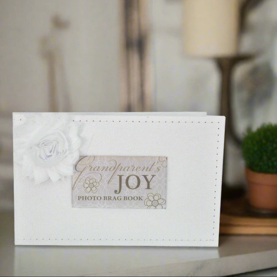 White photo brag book titled &#39;Grandparent&#39;s Joy&#39; on a table in a living room.