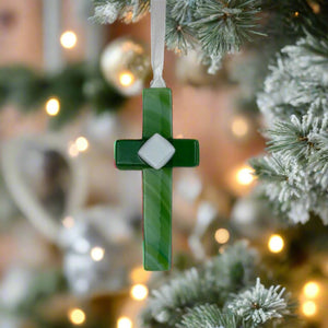3 of 5:Green glass cross with white satin ribbon hanging on a Christmas tree.