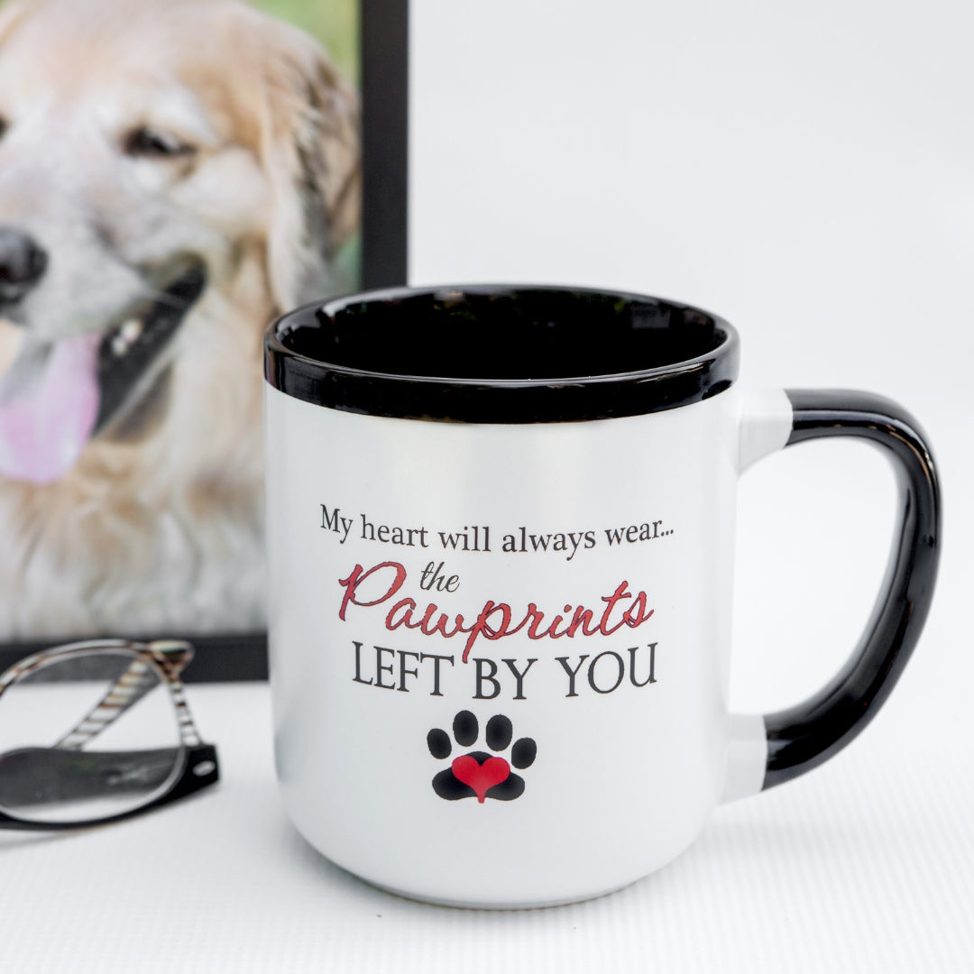 White ceramic mug with black handle and rim. "My Heart will Always wear... the Pawprints Left By You" on front.