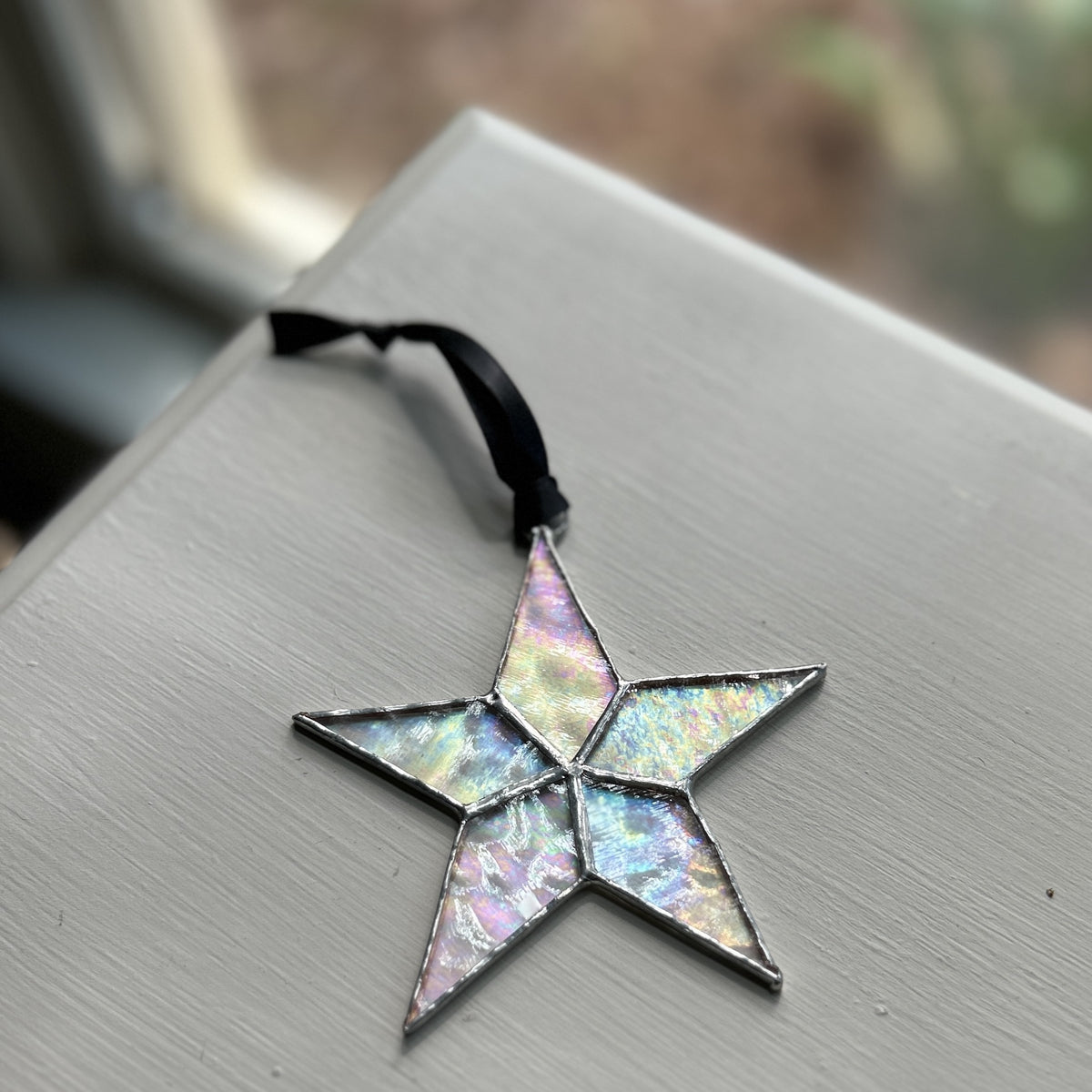 Clear stained-glass star laying on a table showing the colors reflecting from the glass.