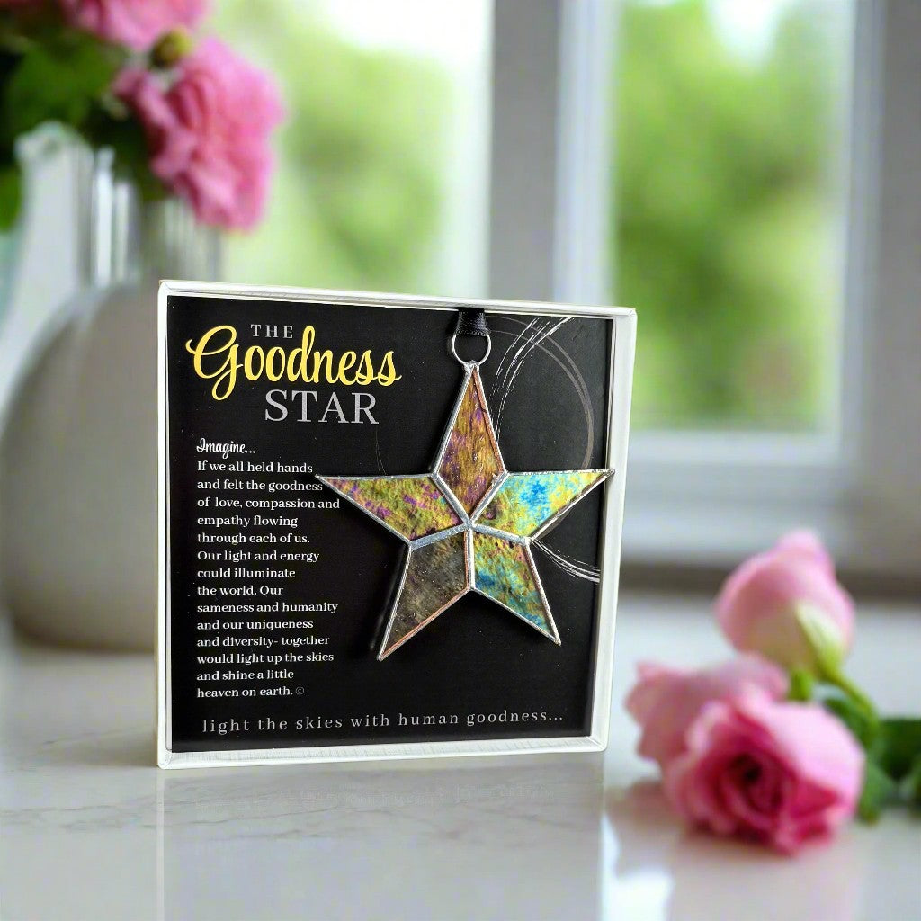 Goodness Star product packaging with a star-shaped ornament on a table with pink flowers.