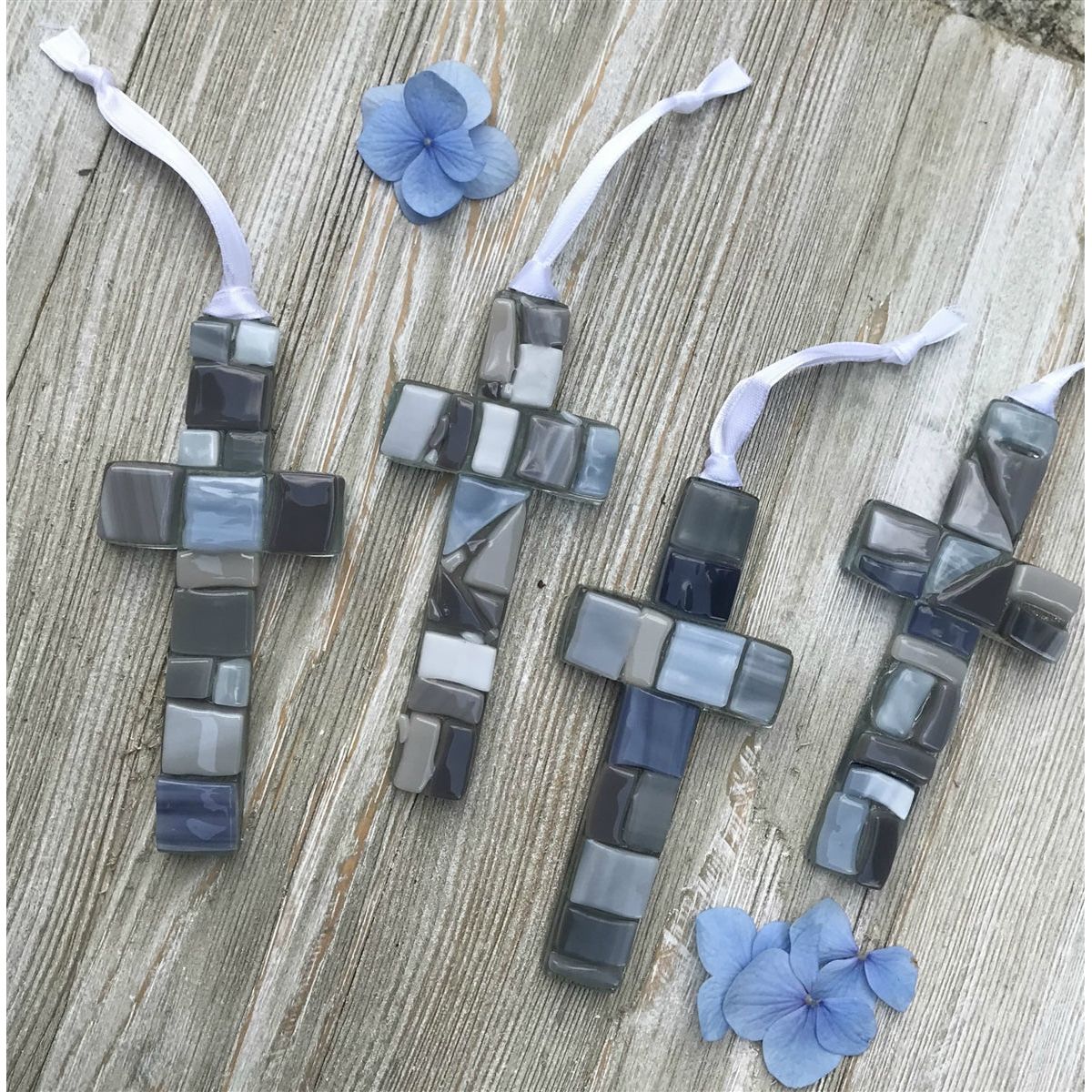 An assortment of gray mosaic crosses, each cross is unique