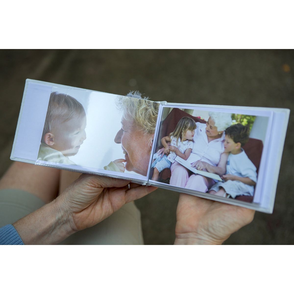 Open photo album being held in hands showing photos in the plastic sleeves.