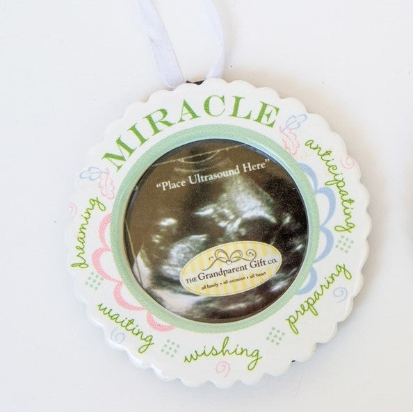 Miracle ornament with white satin ribbon for hanging.