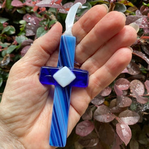 5 of 7:Blue glass cross being held in a hand.
