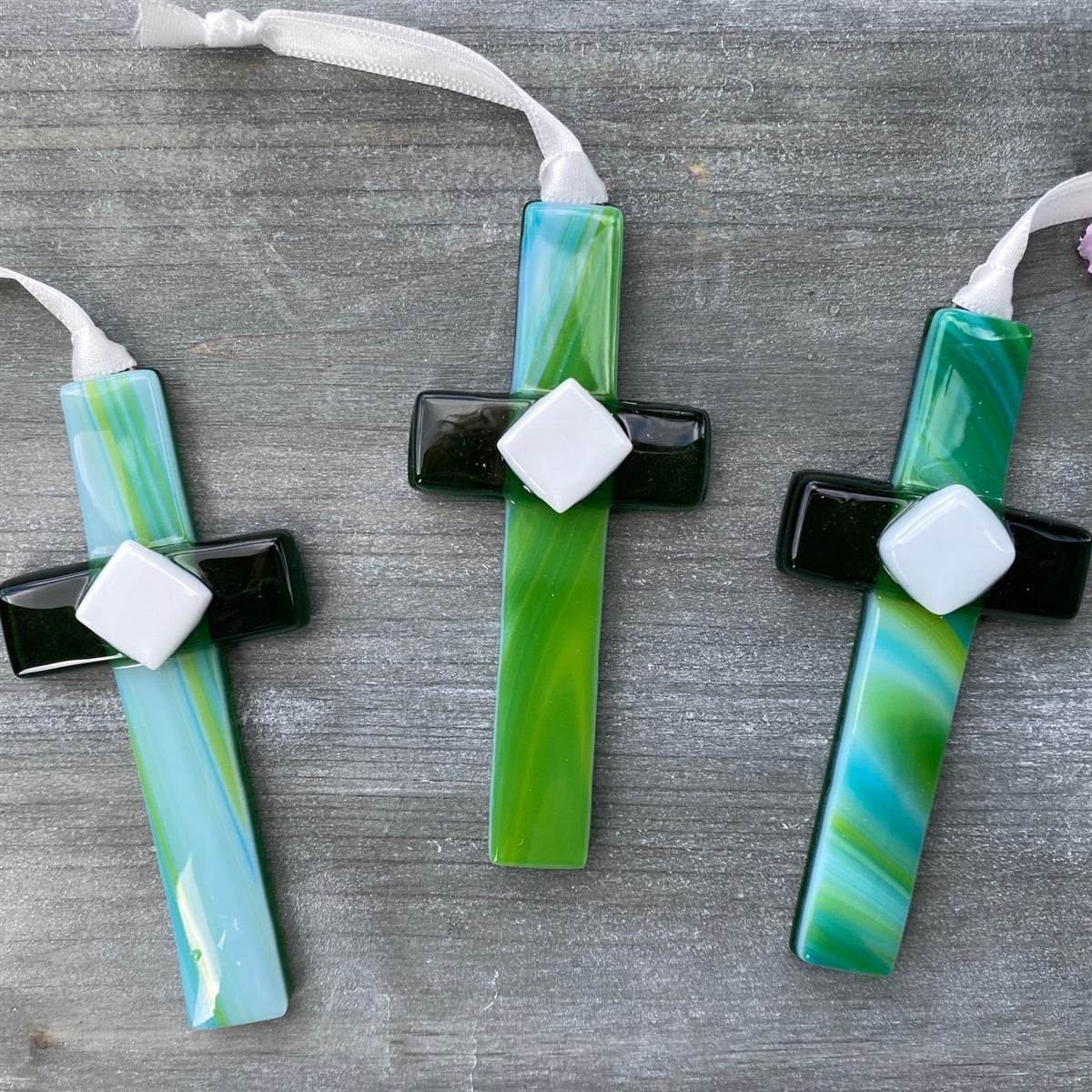 An assortment of green glass crosses with swirls of green and blue.