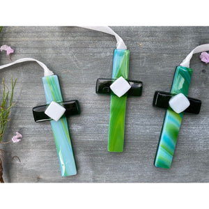 2 of 3:An assortment of green glass crosses with swirls of green and blue.