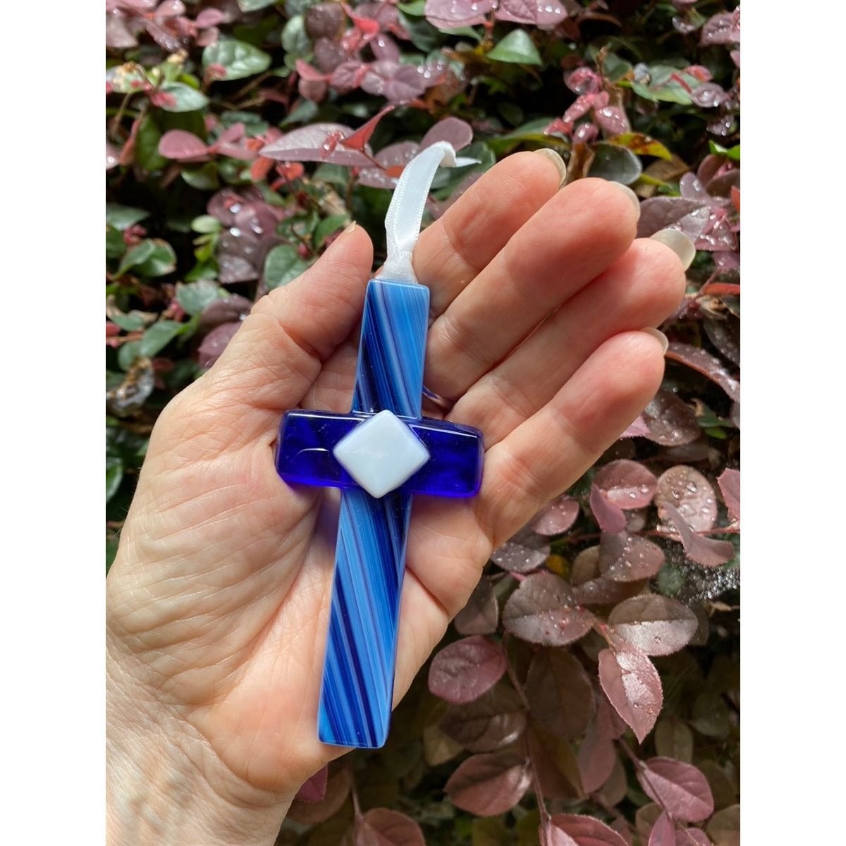 Blue glass cross being held in a hand.