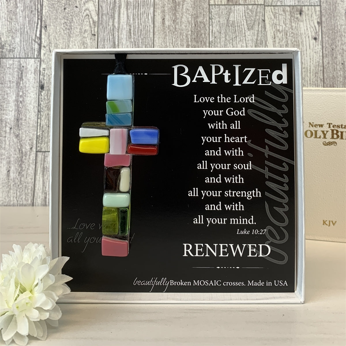 Baptized glass mosaic cross with bible in background.