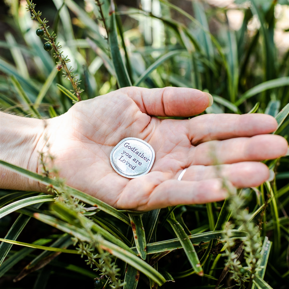 Pewter coin being held in hand.