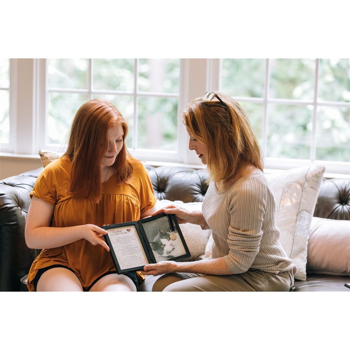 Two women exchanging the &quot;Where I&#39;ll Always Be&quot; frame.