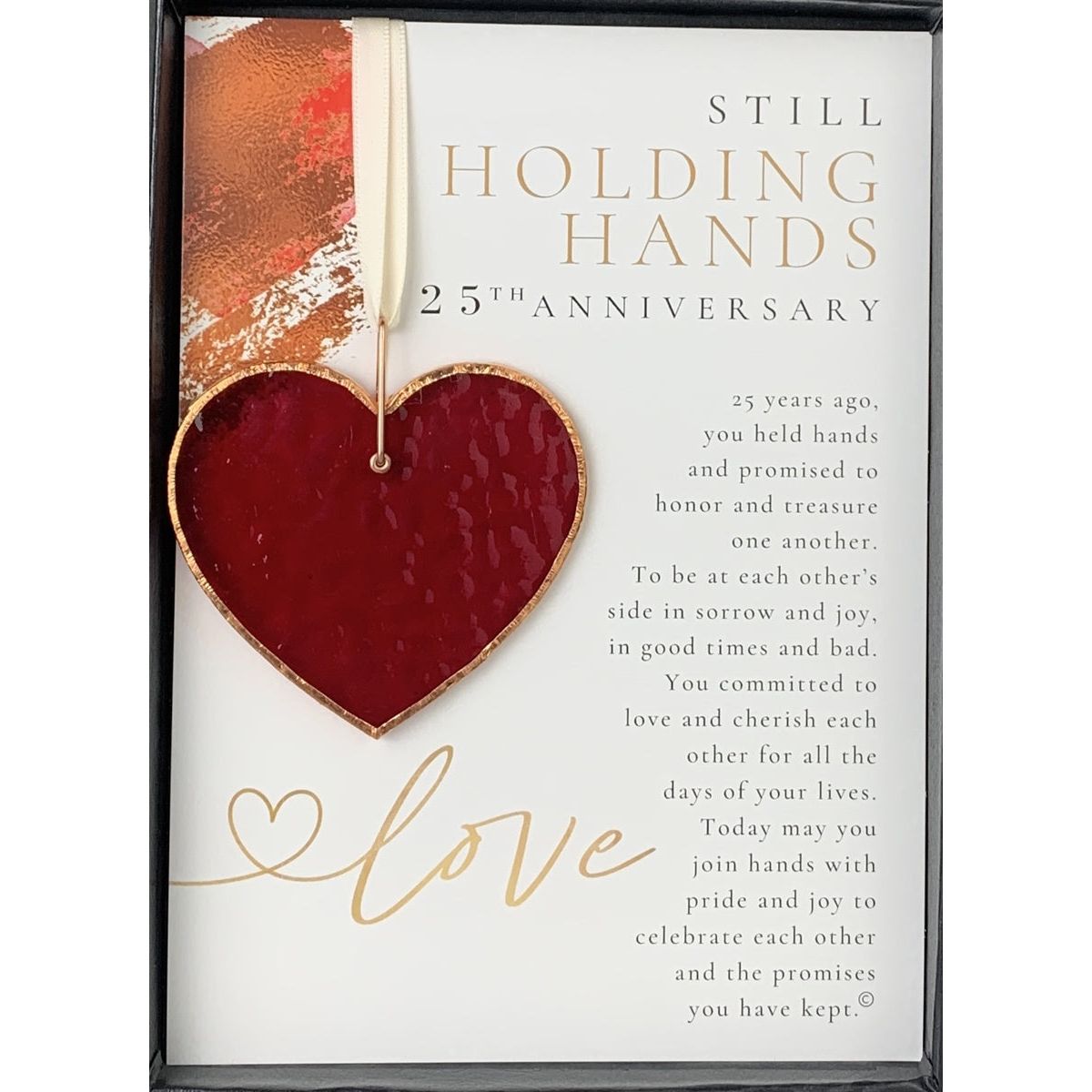 Stained glass red heart edged with copper and packaged with &quot;Still Holding Hands 25th Anniversary&quot; sentiment in black box with clear lid.