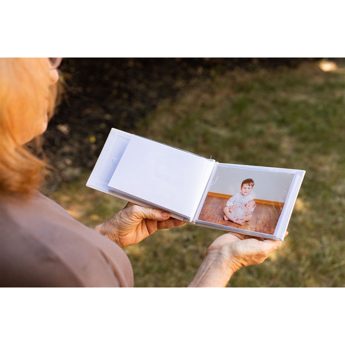 Open photo album being held in hands showing photos in the plastic sleeves.