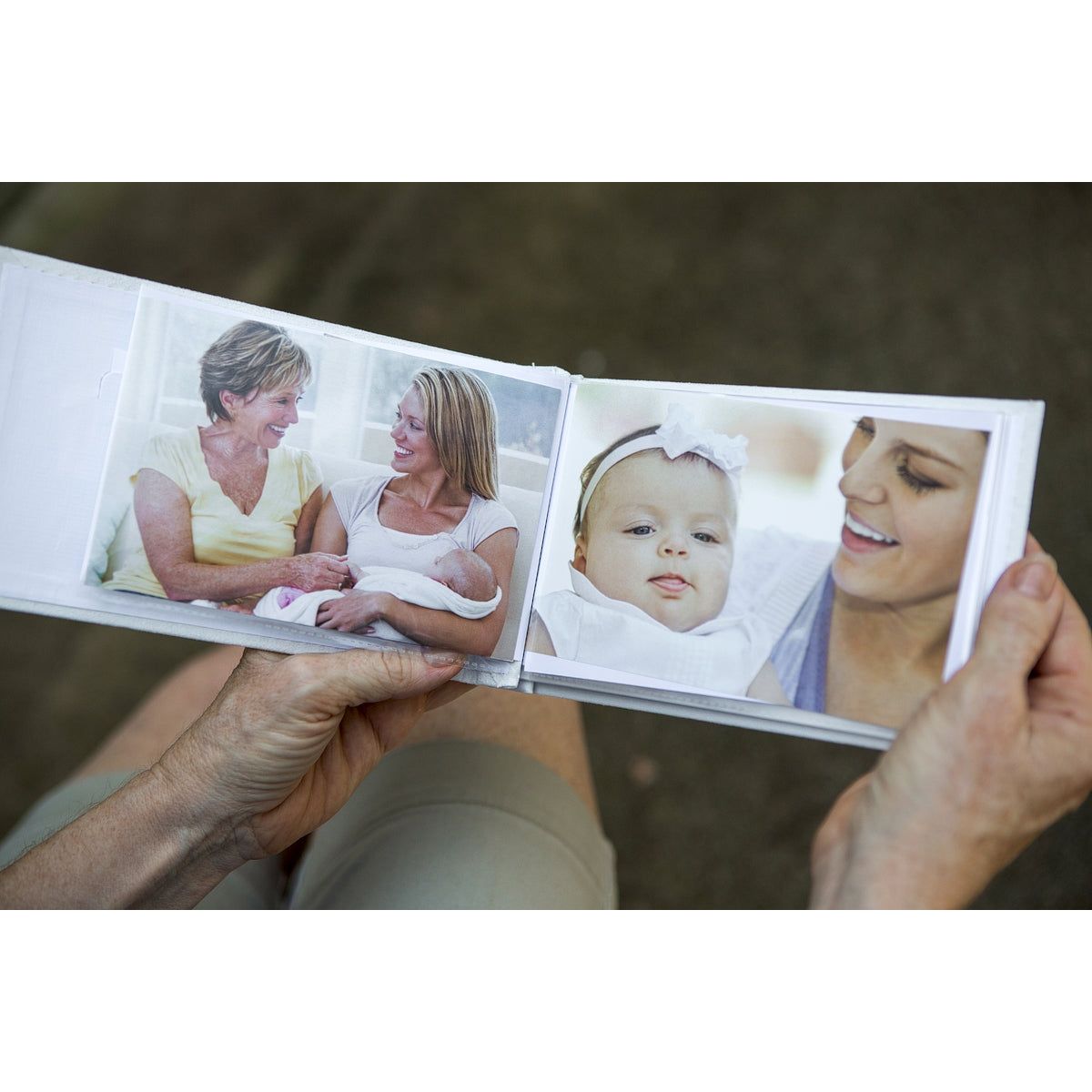 Open photo album being held in hands showing photos in the plastic sleeve.